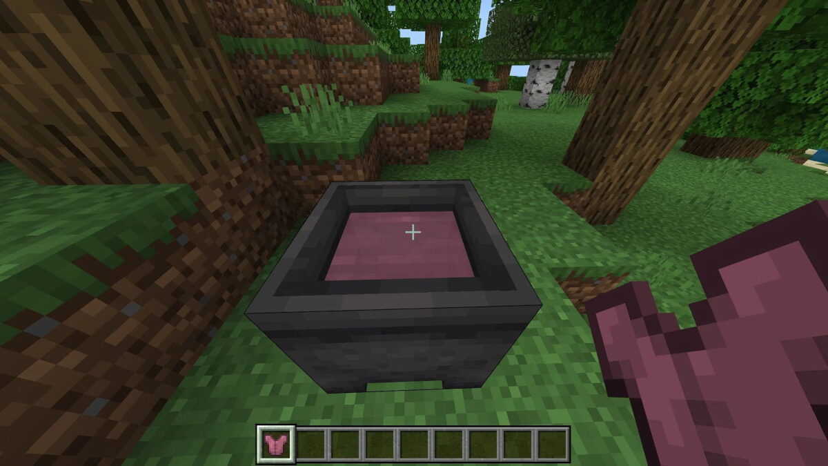 Capture d'écran d'un chaudron rempli d'eau teintée de rose dans Minecraft Bedrock Edition, montrant le processus de teinture d'une armure en cuir