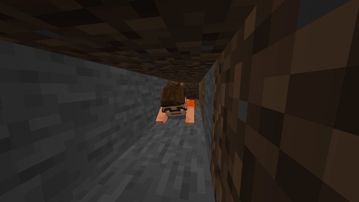 Un joueur de Minecraft rampe dans une grotte étroite, fonction de crawlé initialement non prévue dans Minecraft.