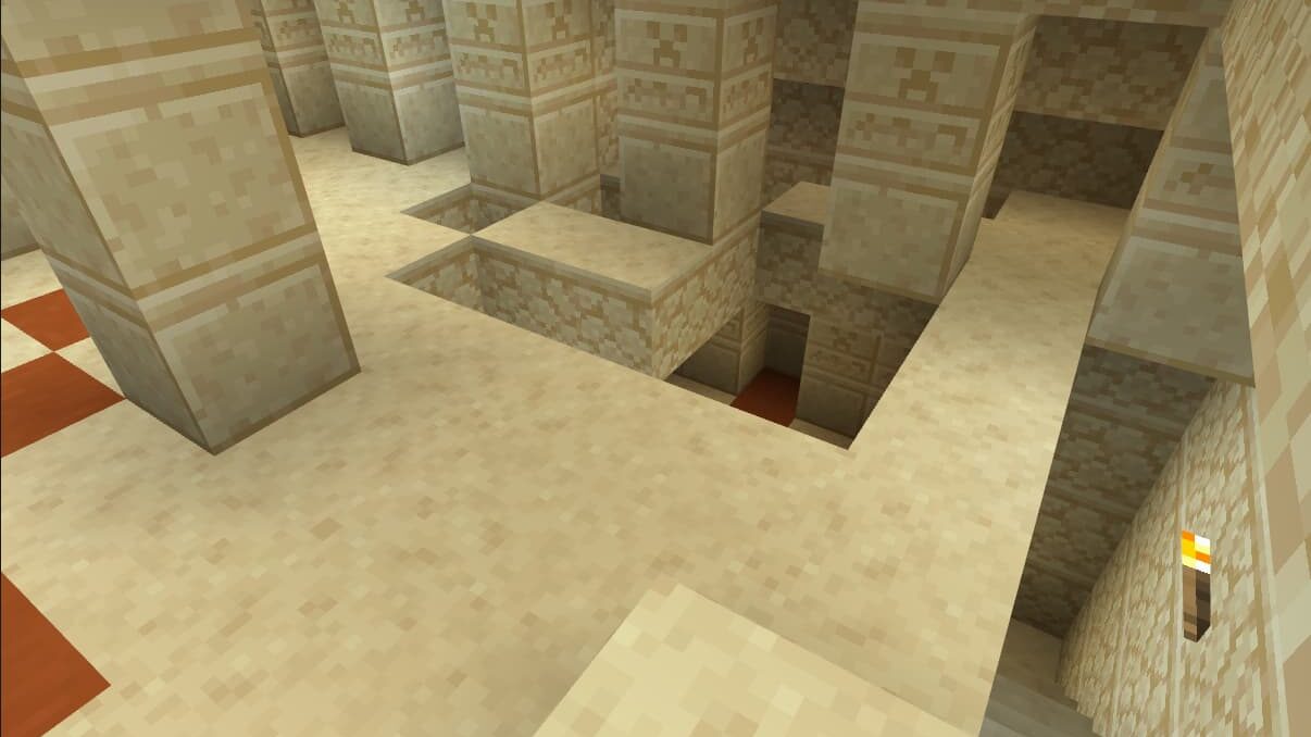 Vue d'une pièce excavée dans une pyramide du désert de Minecraft avec des escaliers effondrés.