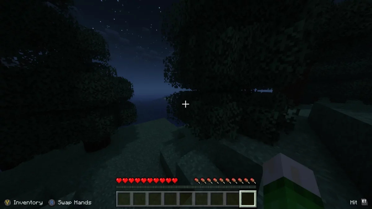 Vue de nuit dans Minecraft avec les icônes de bouton d’une manette affichées à l’écran grâce au mod MidnightControls.