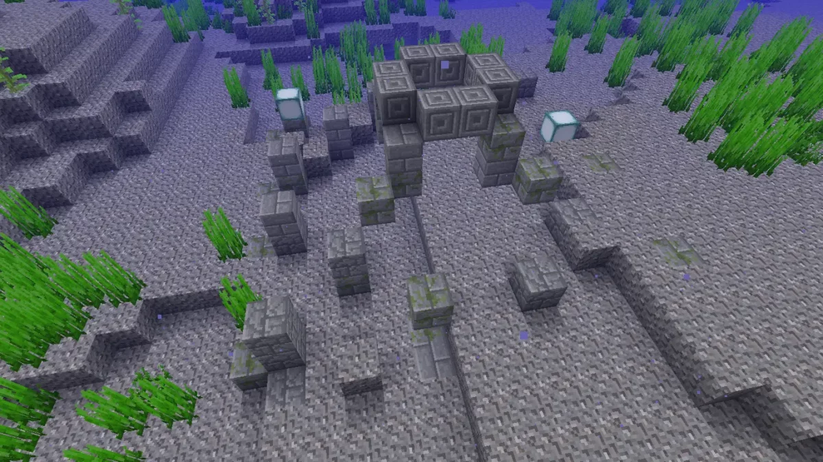 Restes de ruine sous-marine froide dans Minecraft, avec des piliers de pierre taillée émergeant du gravier