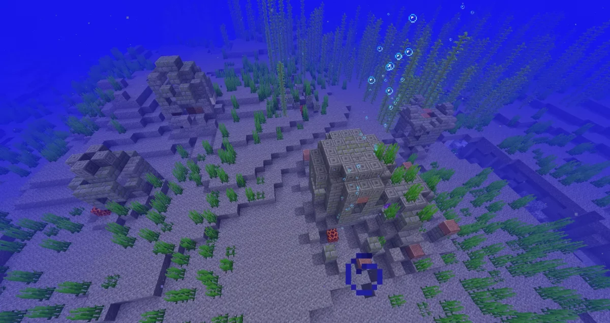 Petit village sous-marin en ruine dans Minecraft, composé de plusieurs structures froides entourées de varech