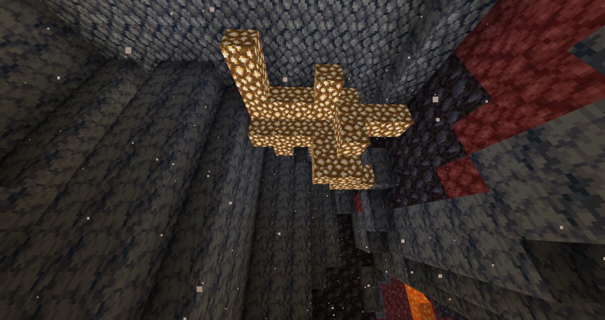 Amas massif de blocs de pierre lumineuse suspendu dans une caverne du Nether dans Minecraft
