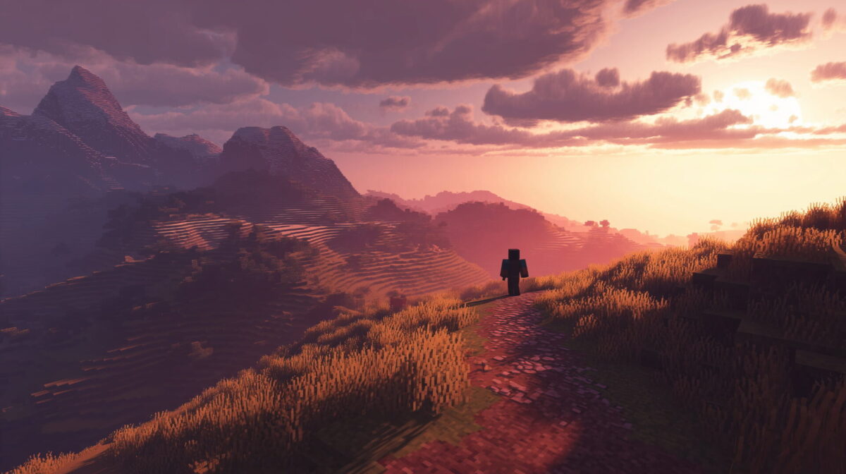 Un personnage de Minecraft marche sur un sentier au coucher du soleil, dans un paysage de collines et montagnes.