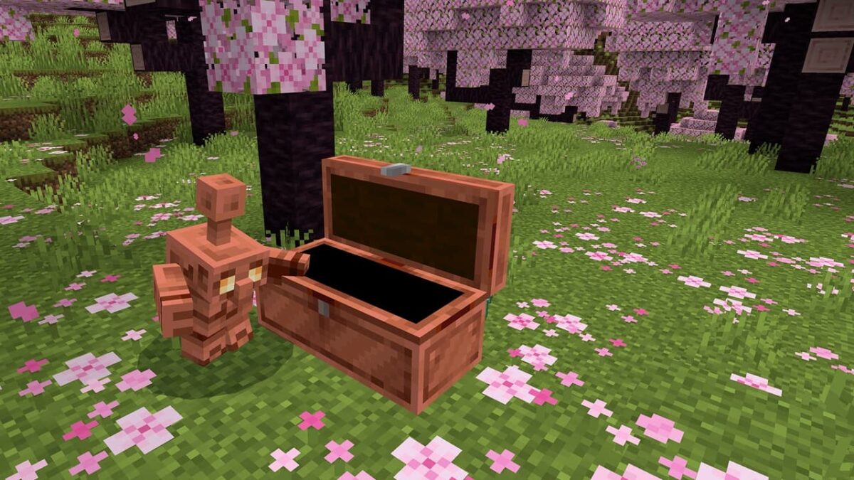 Un golem de cuivre se tient près d’un coffre en cuivre ouvert dans une clairière fleurie sous des cerisiers en fleurs dans Minecraft.