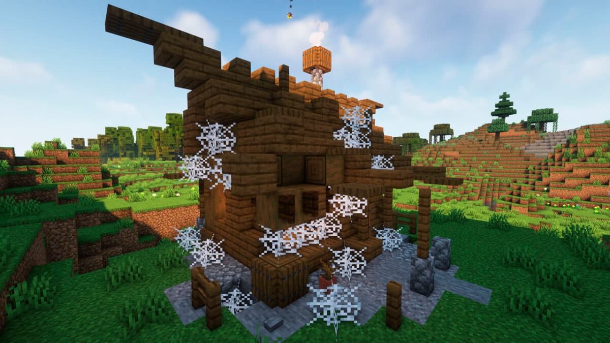 Maison abandonnée infestée de toiles d’araignée, générée par le mod Medieval Buildings dans Minecraft, au cœur d’un paysage vallonné.