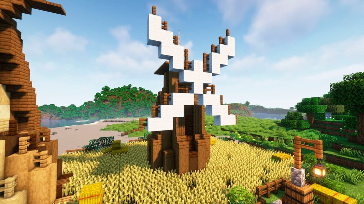 Moulin à vent en bois au milieu d’un champ de blé, structure du mod Medieval Buildings dans Minecraft.