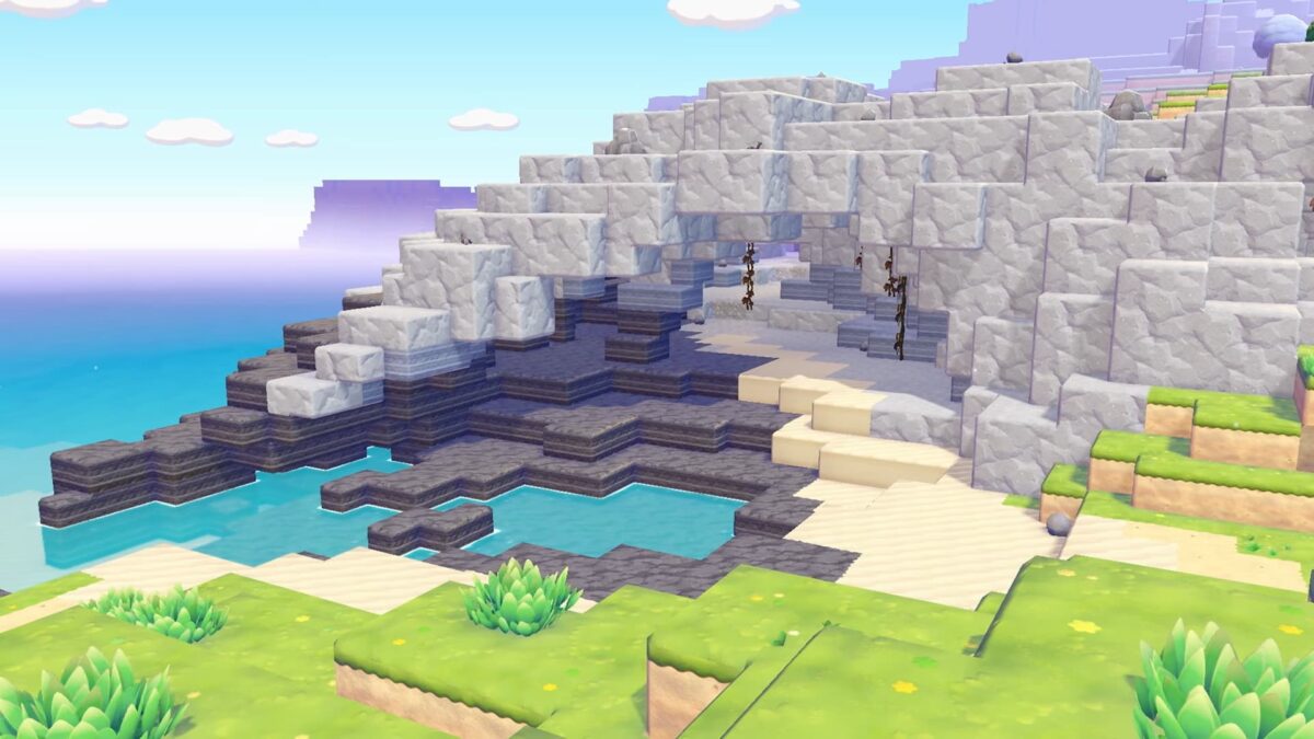 Paysage côtier dans Pokémon Pokopia avec une arche rocheuse, une plage de sable et une eau turquoise.
