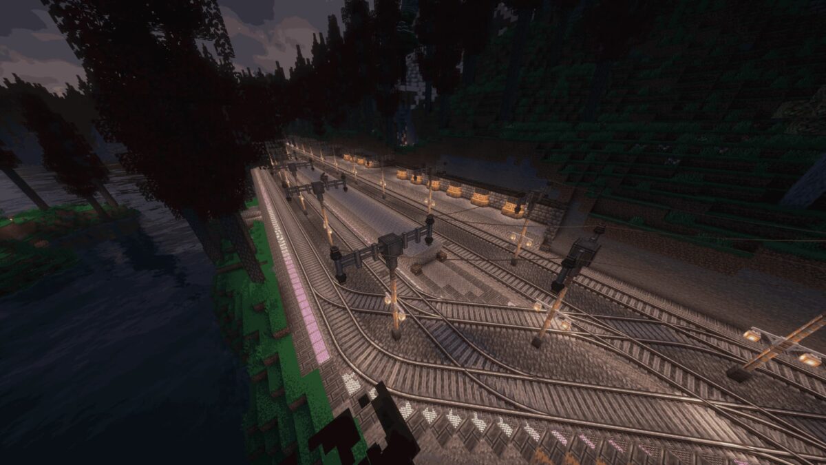 Vue aérienne d’un vaste réseau ferroviaire éclairé la nuit dans le modpack Minecraft All Of Create.