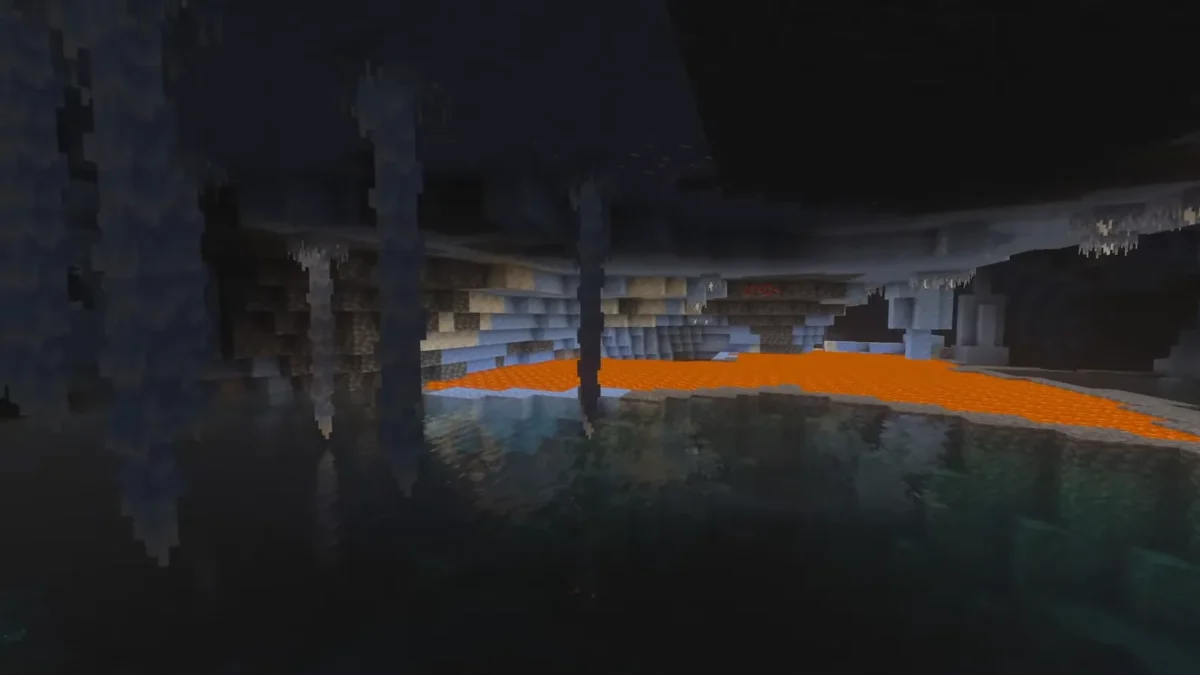 Un plan large montre un lac souterrain bordé de glace avec de la lave au fond dans Minecraft