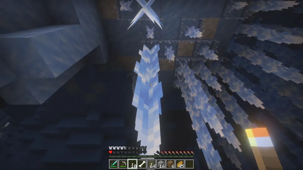 Une torche tenue près d’une formation glacée illustre les interactions lumineuses présentées dans Minecraft